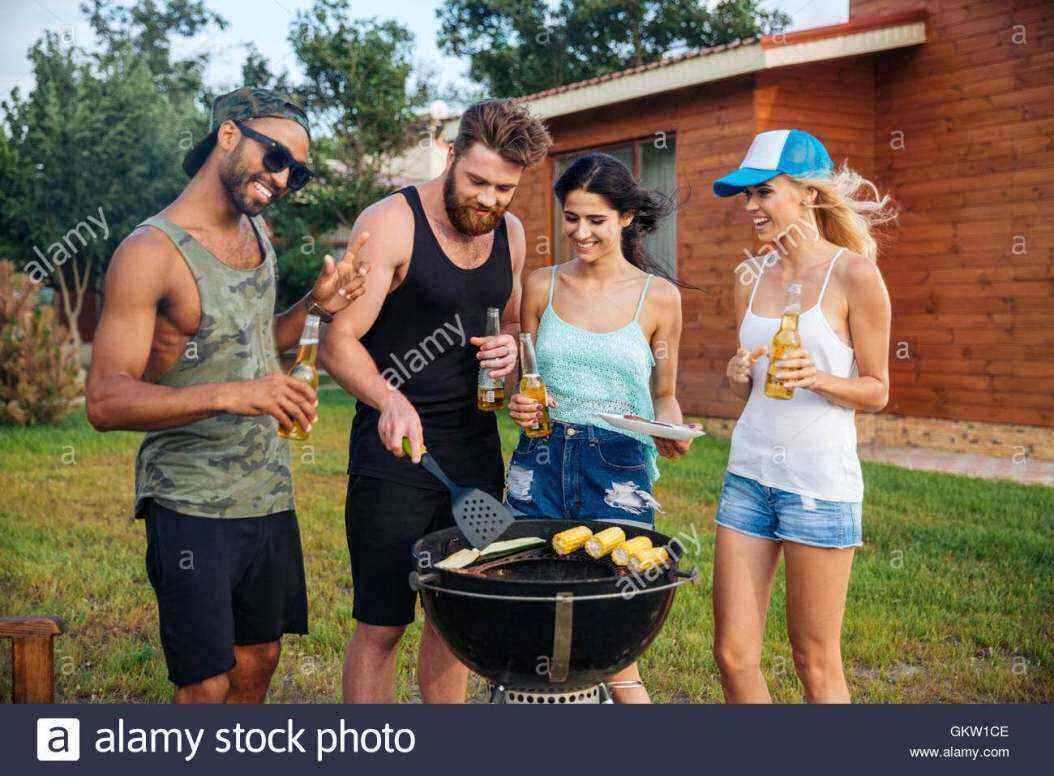 group-of-smiling-young-people-drinking-beer-and-cooking-on-barbeque-GKW1CE.jpg